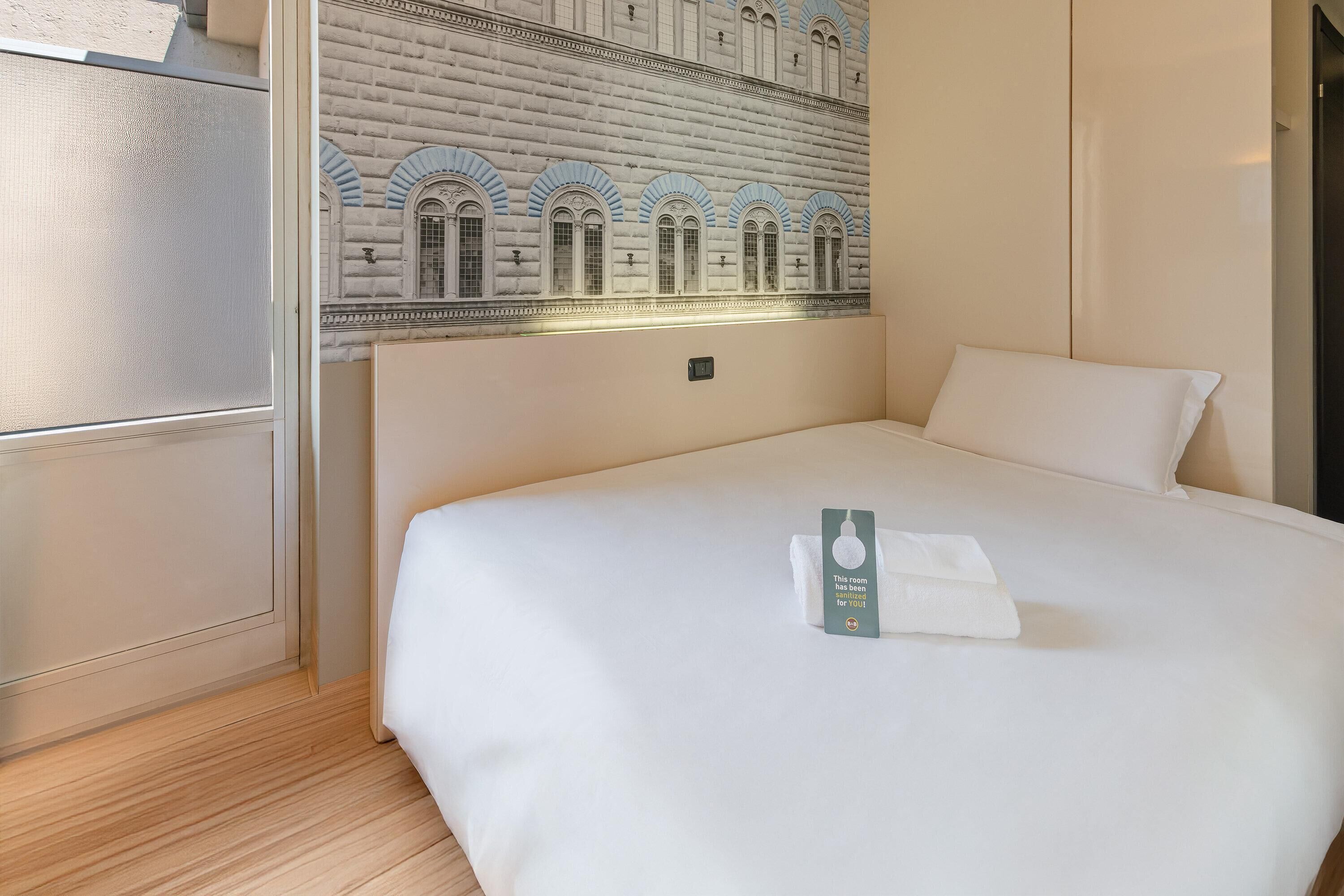 Une chambre d’hôtel avec un grand lit, un plancher en bois et un mur orné d’une fresque décorative.