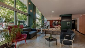 Un vestíbulo amplio con mobiliario moderno, ventanas grandes y plantas de interior.