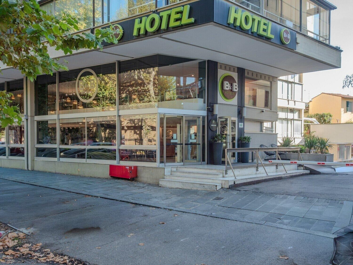 A modern hotel with a glass facade, a visible entrance, and a sign indicating it is part of the B&B Hotels chain.