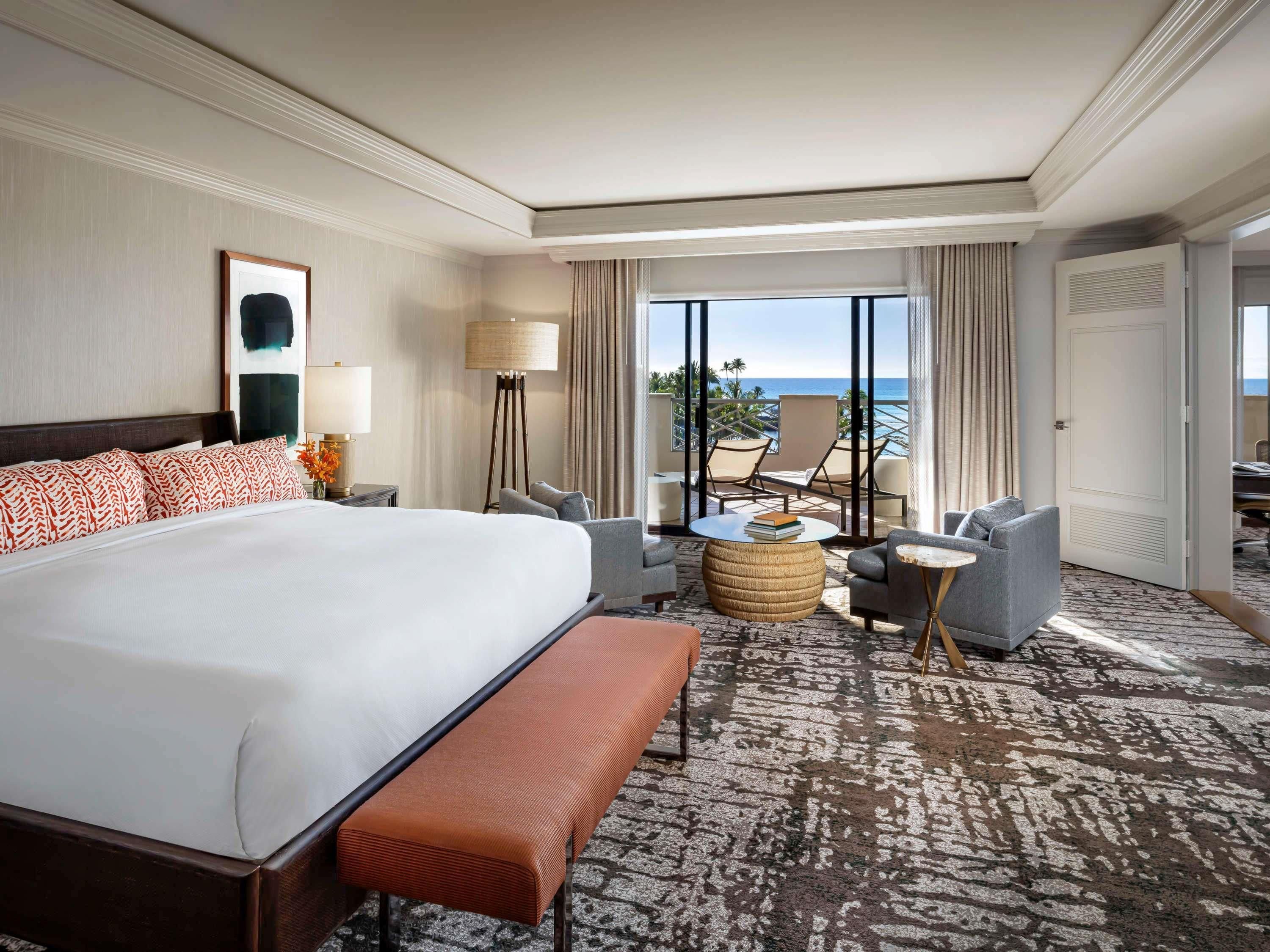 Une chambre d’hôtel avec un grand lit, un coin salon avec vue et un balcon.
