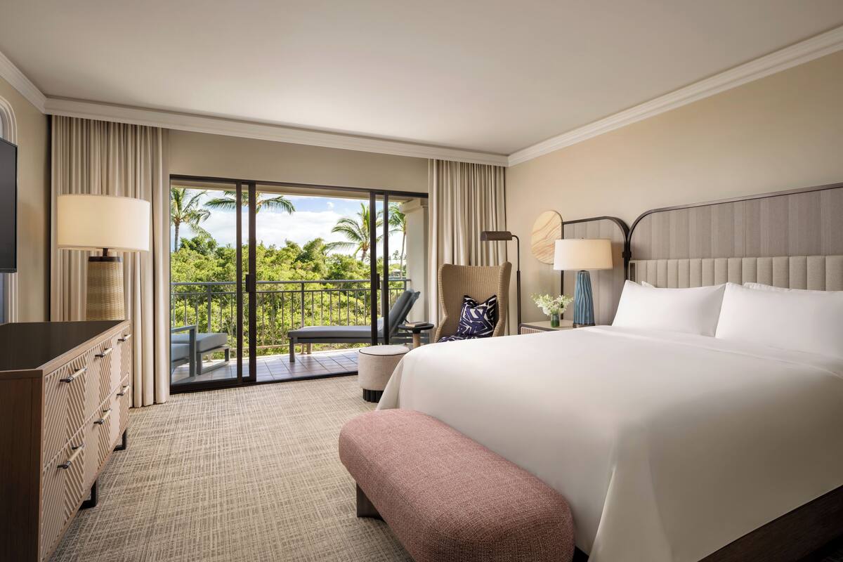 A hotel room with a large bed, a desk, a chair, and a view of the outdoors.
