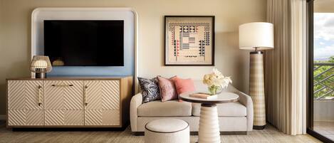 A modern living room with a sofa, ottoman, side table, and a flat-screen TV mounted on the wall.