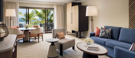 A hotel room with a balcony, a dining area, a sofa, and a coffee table.