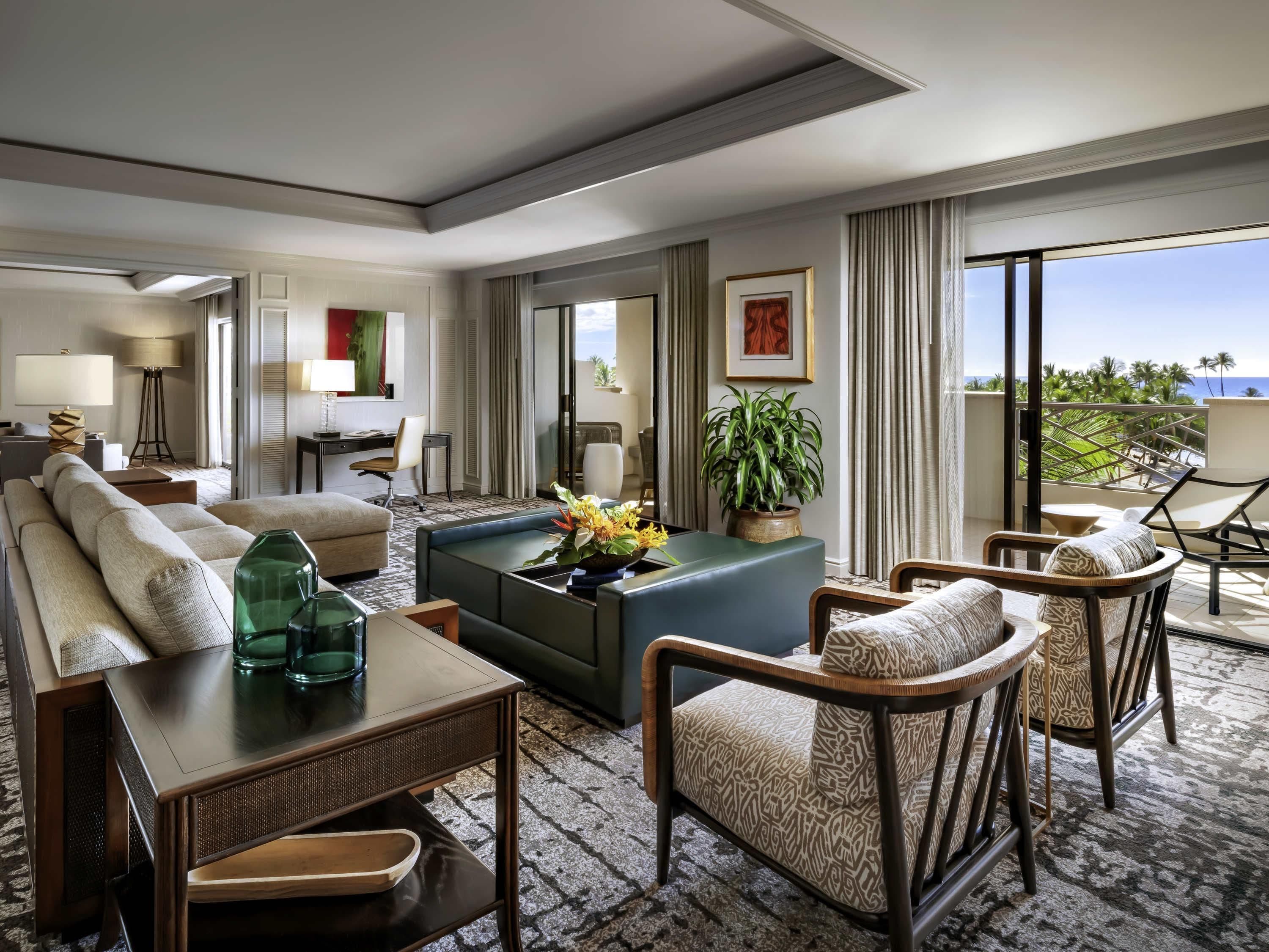 A hotel room with a sofa, a coffee table, a dining area, and a balcony with a view.