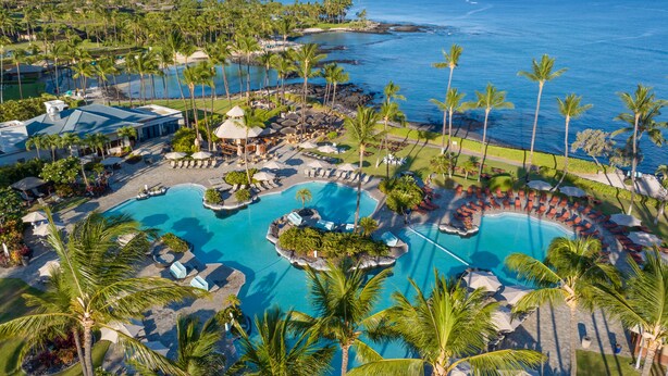 Ein Resort mit großem Pool, Palmen und Blick auf den Ozean.