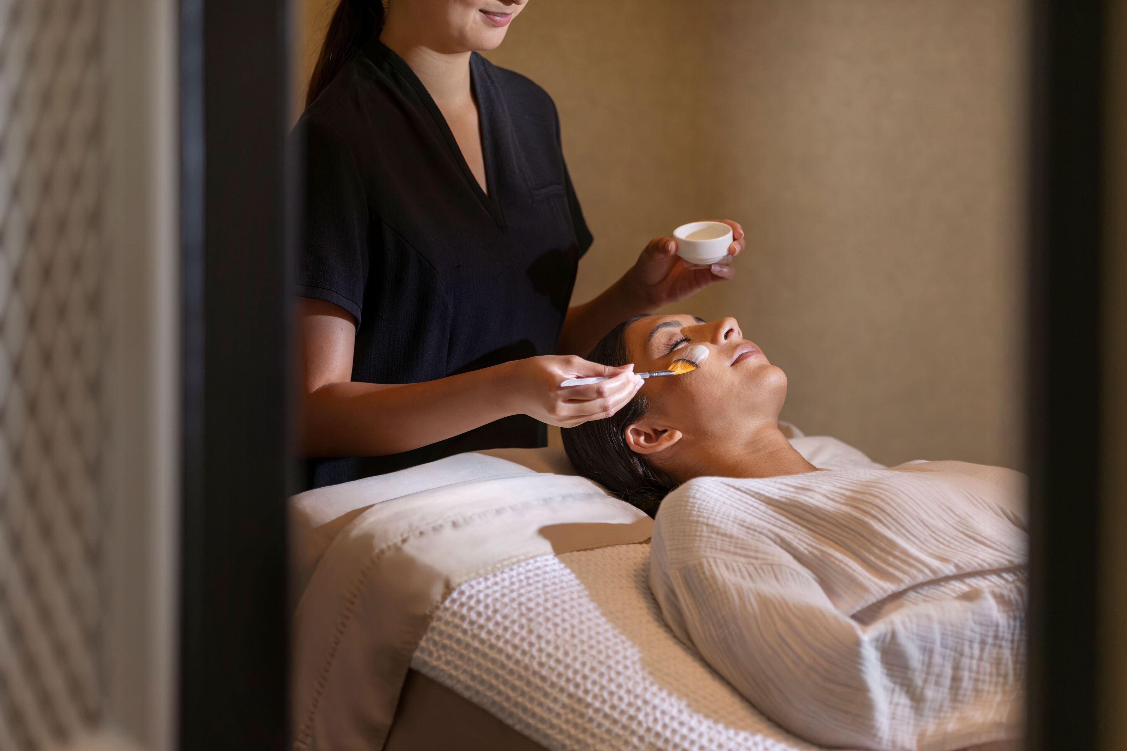 A person lying on a bed receiving a facial treatment.