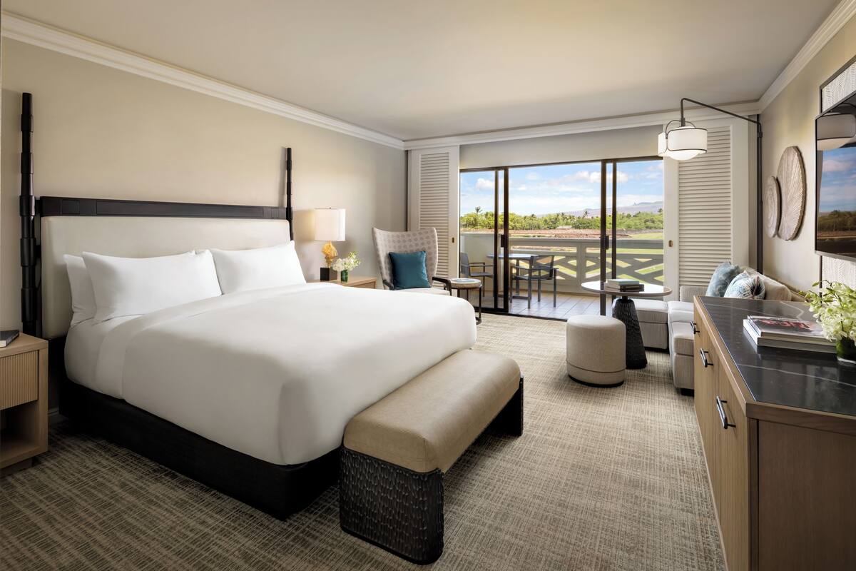 A hotel room with a large bed, a desk, a chair, and a view of the outdoors.