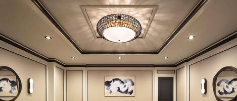 A spacious conference room with a patterned carpet, a central chandelier, and artwork on the walls.