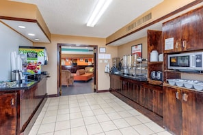 A hotel lobby with a reception desk, seating area, and a kitchenette.