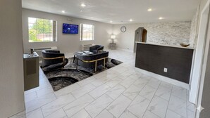 A spacious living area with a fireplace, a flat-screen TV, and a stone accent wall. - Lakeside Inn (Guntersville)