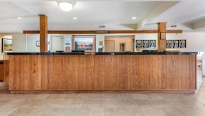 A reception desk with a wooden finish, a non-smoking sign, framed certificates on the wall, and a clock.