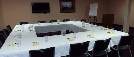 A conference room with a long table, chairs, water glasses, and a whiteboard.
