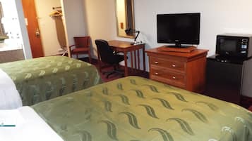 A hotel room with two beds, a desk with a chair, a television, and a microwave.
