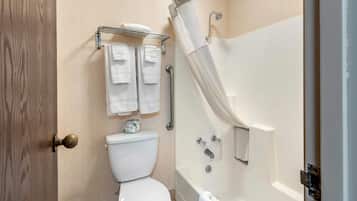 Un baño con inodoro, ducha con puerta de vidrio y toallero con varias toallas.