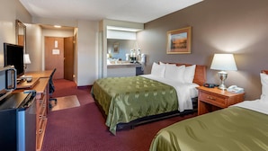 A hotel room with a bed, a desk with a computer, a mirror, a lamp, and a telephone.