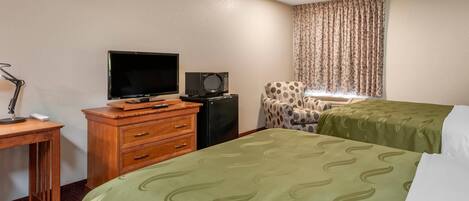 A hotel room with two beds, a desk with a television, a dresser, and a chair.