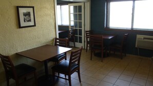 A dining area with a table and chairs, a door, and a window with blinds. - Relax Inn (Davenport)