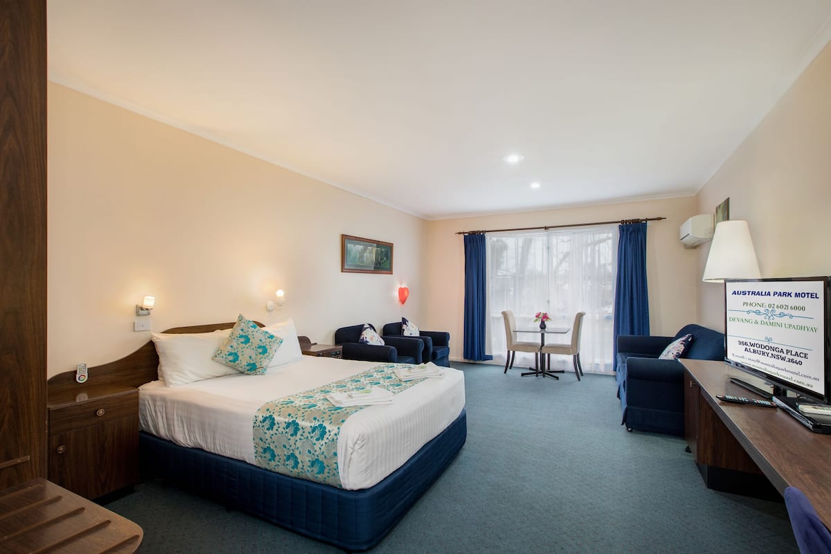 A hotel room with a bed, bedside tables, a desk, a chair, and a window with curtains.