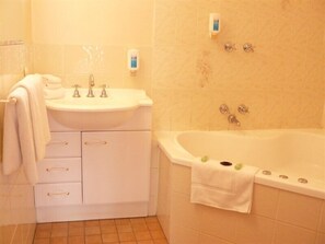 A bathroom with a sink, two faucets, a bathtub, and a towel rack. - Australia Park Motel (South Albury)