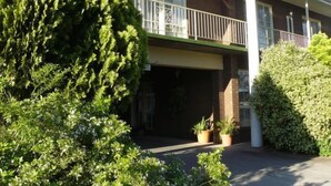 Un edificio de dos pisos con balcón, garaje y plantas en macetas.