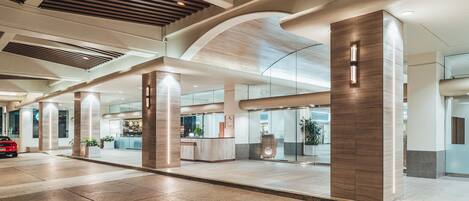 A spacious lobby with a reception desk, large pillars, and a modern ceiling design.