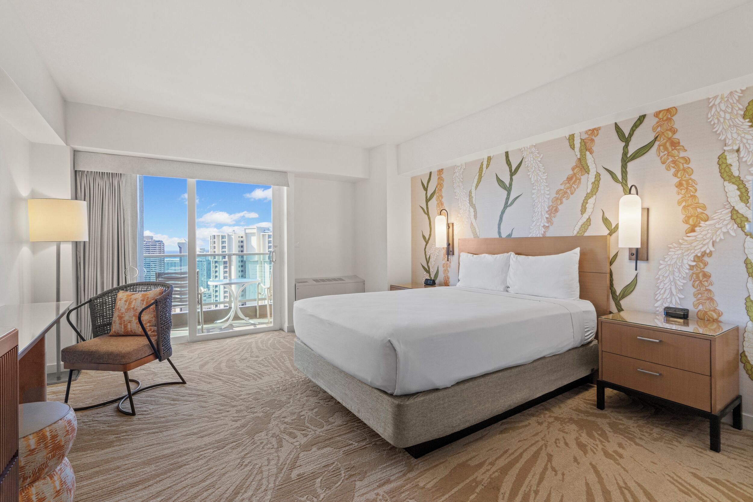 Habitación de hotel con una cama grande, una silla, un escritorio y vistas a la ciudad.