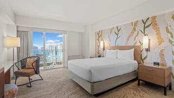 Habitación de hotel con una cama grande, una silla, un escritorio y vistas a la ciudad.