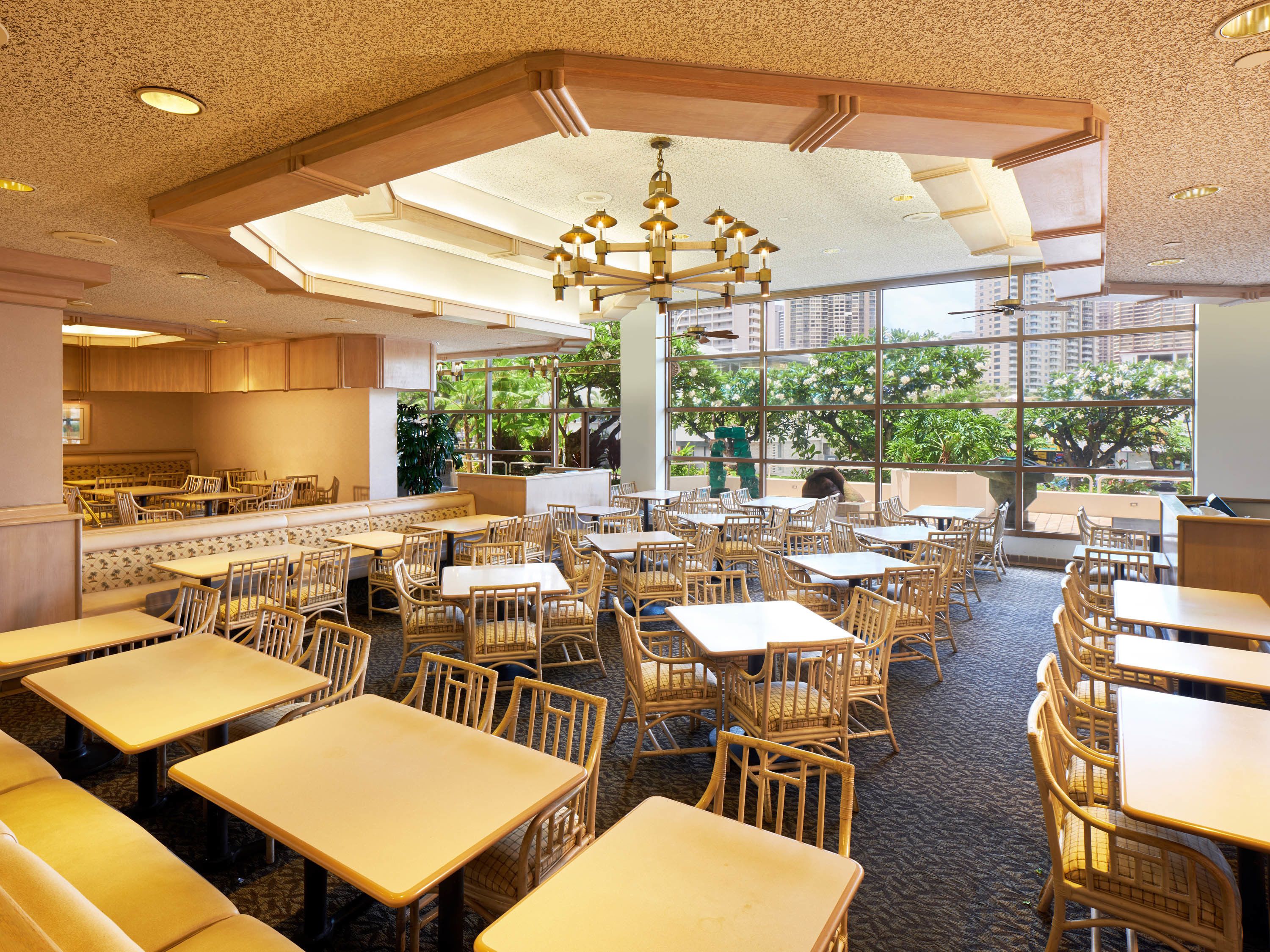 A spacious restaurant with high ceilings, large windows, and a variety of seating arrangements including tables and booths.