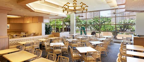 A spacious restaurant with high ceilings, large windows, and a variety of seating arrangements including tables and booths.