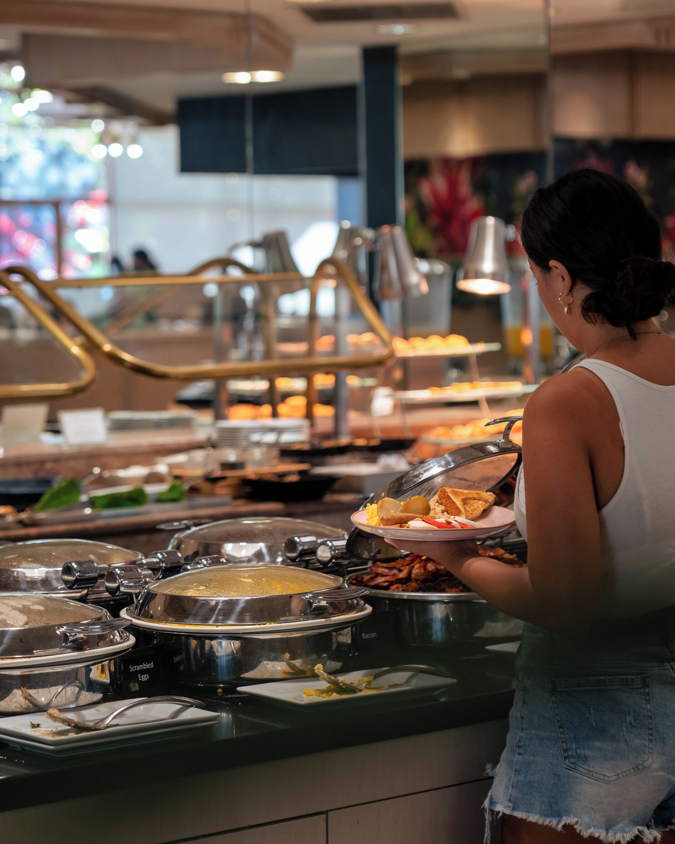 A buffet area with various food stations and a person serving themselves.