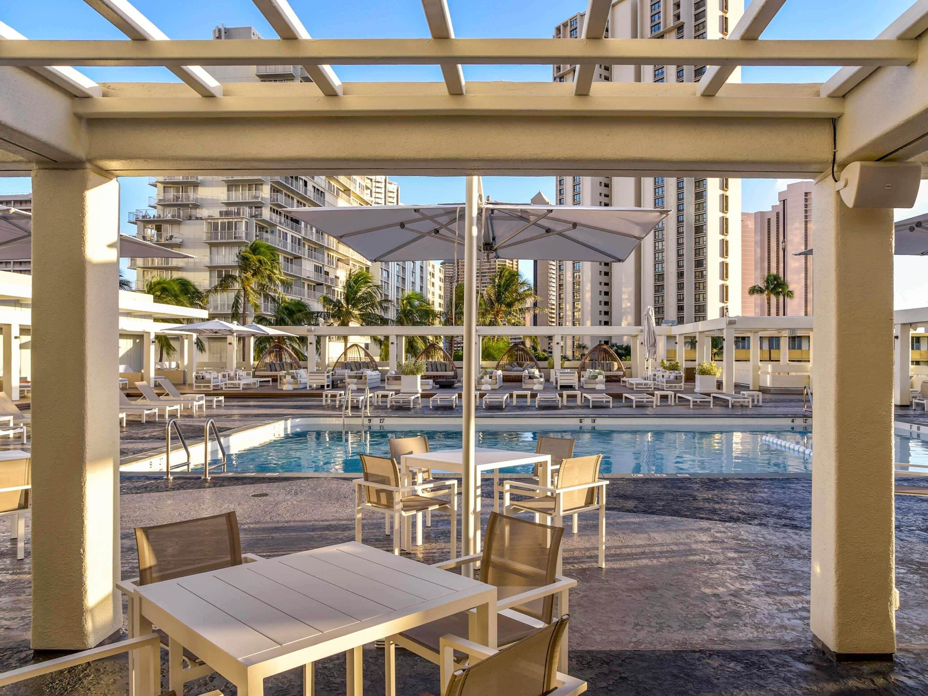 A pool area with lounge chairs and umbrellas, surrounded by high-rise buildings.