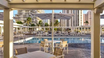 A pool area with lounge chairs and umbrellas, surrounded by high-rise buildings.