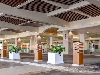 A high-rise hotel with multiple floors, a covered entrance, and a clear sky. at Ala Moana Hotel by Mantra