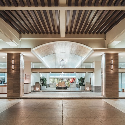 A spacious lobby with a high ceiling, large windows, and a central seating area.