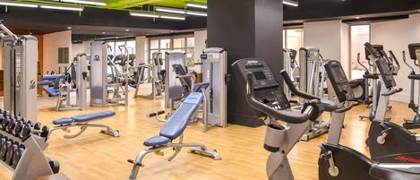 Un gimnasio con diversos equipos de ejercicio, incluyendo cintas de correr y máquinas de pesas.