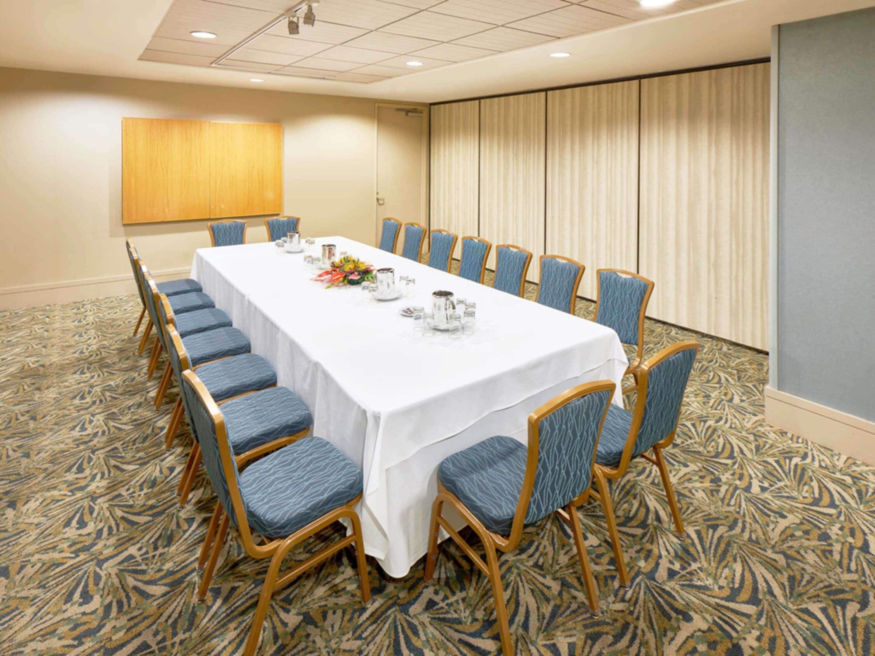 A conference room with a long table, blue chairs, and a patterned carpet.