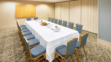 A conference room with a long table, blue chairs, and a patterned carpet.