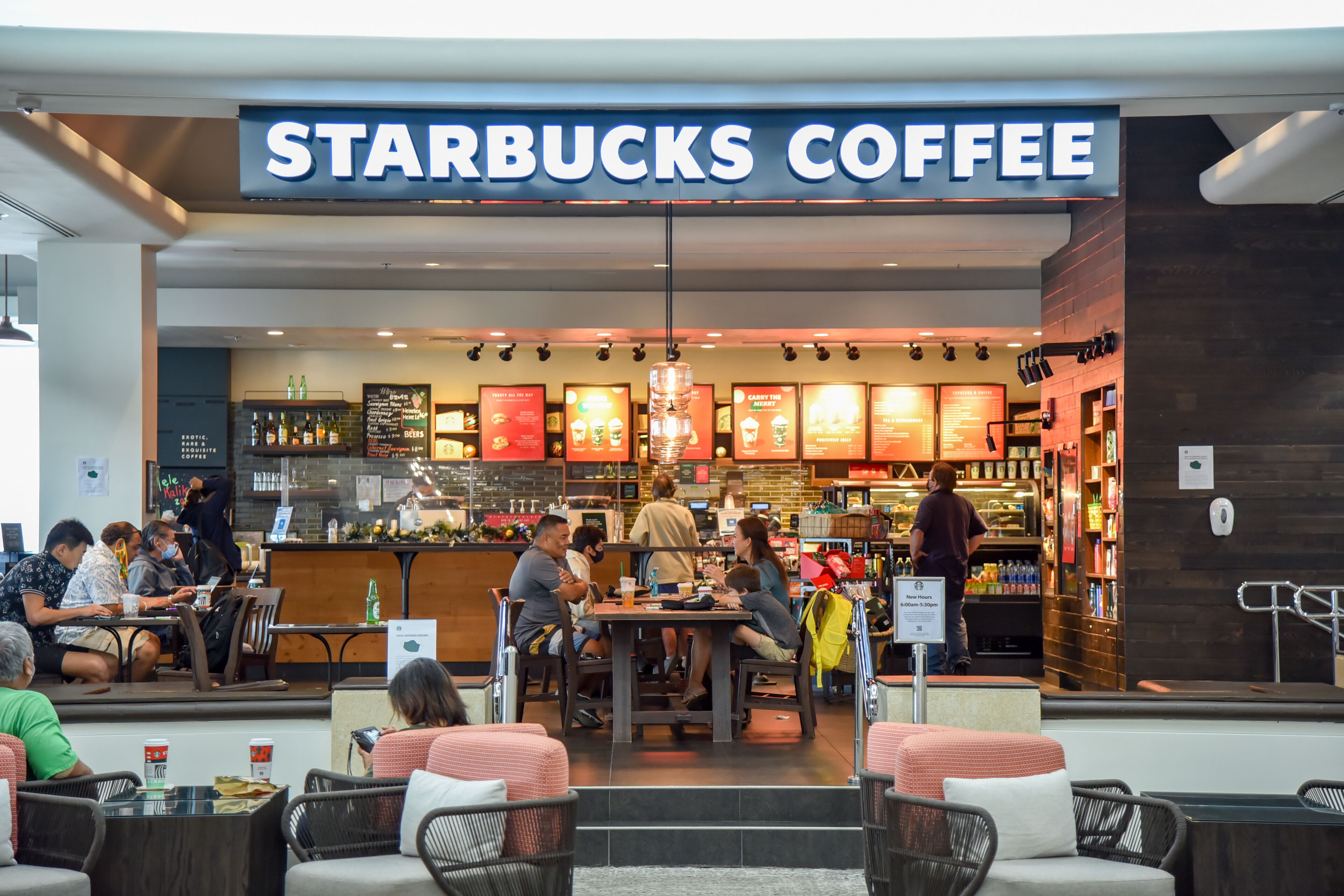 A Starbucks Coffee with outdoor seating, a bar area, and a variety of menu boards.