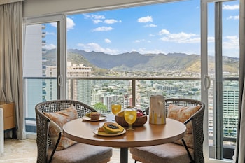 A cozy café with a wooden bar, seating area, and shelves stocked with snacks and beverages. at Ala Moana Hotel by Mantra