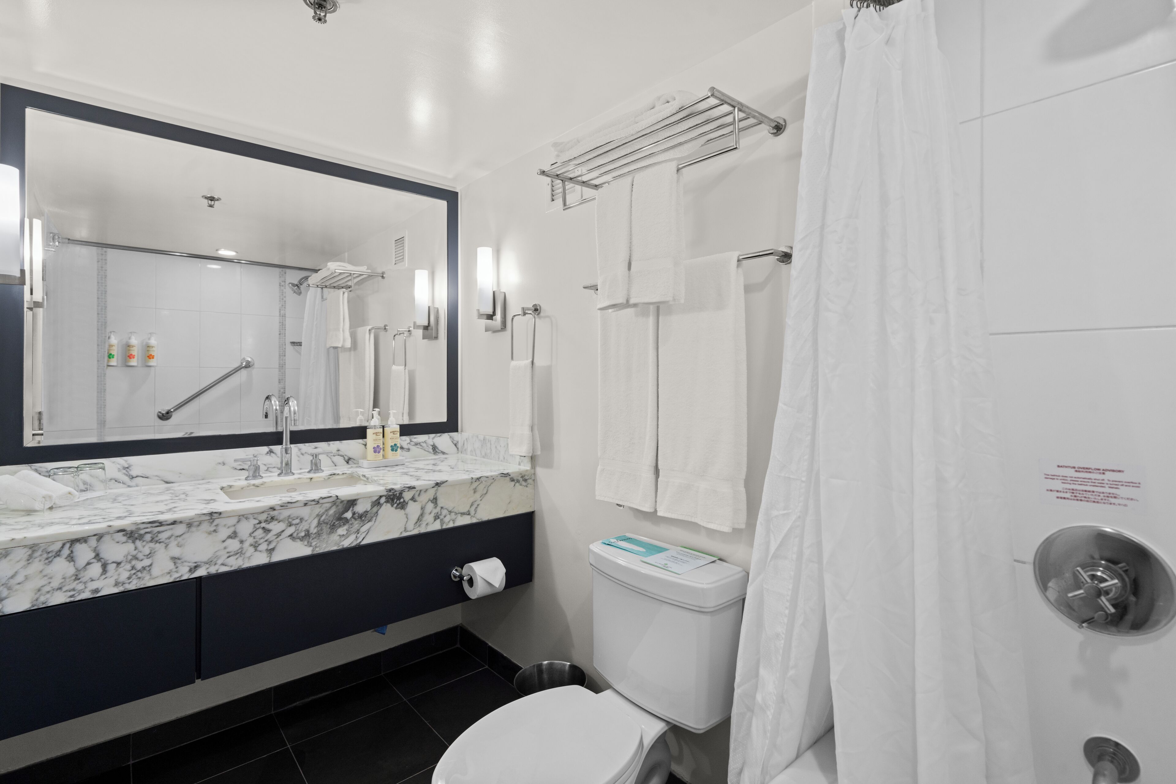 A modern bathroom with a marble sink, a toilet, and a shower area.