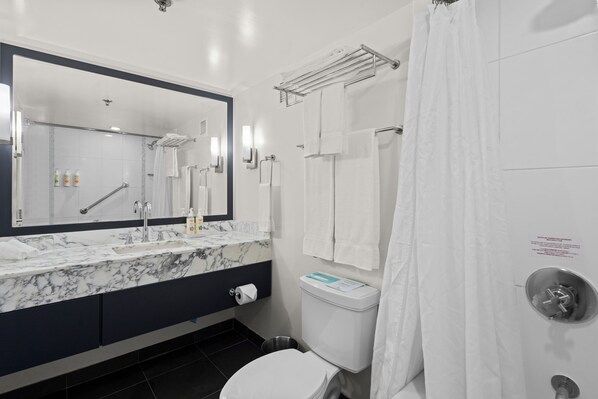 A modern bathroom with a marble sink, a toilet, and a shower area.