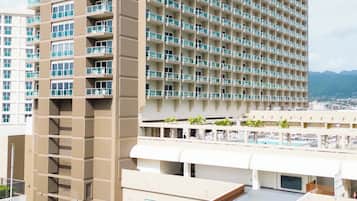 Un hotel de gran altura con varios balcones, una piscina en la azotea y vistas panorámicas de la ciudad.