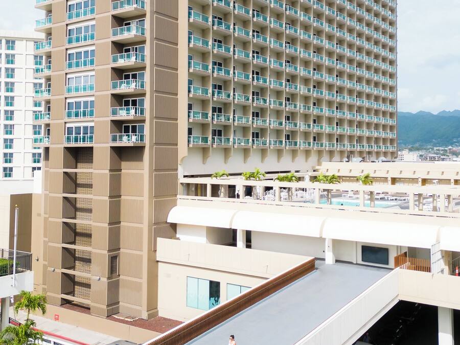 Un hotel de gran altura con varios balcones, una piscina en la azotea y vistas panorámicas de la ciudad.