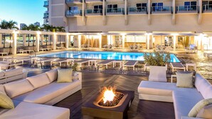 Zona de piscina en la azotea con sillas de descanso, una chimenea y vistas a un edificio.