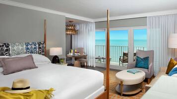 A hotel room with a large bed, a balcony with a view, a small round table, and a chair.
