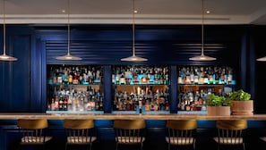 Un bar doté de plusieurs étagères remplies de bouteilles d’alcool, d’un comptoir et de plusieurs tabourets de bar.