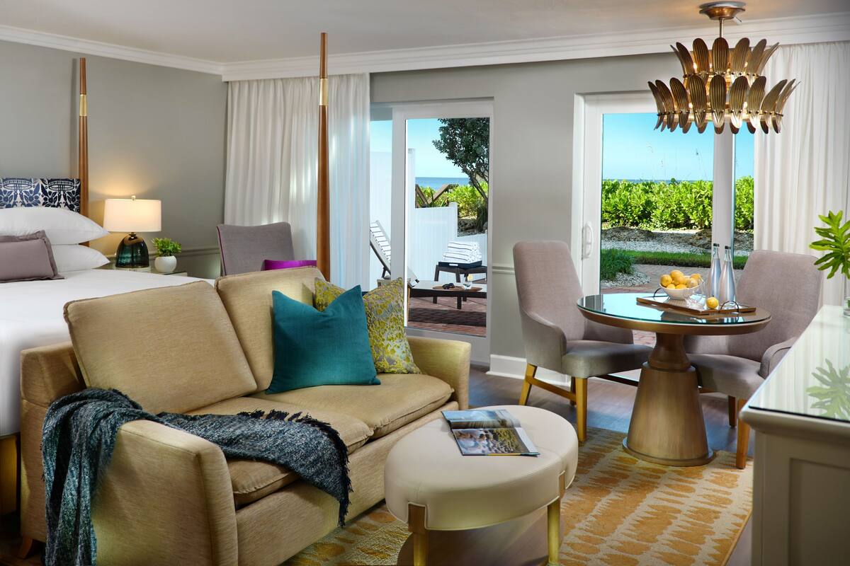Une chambre d’hôtel avec un lit, un canapé, une table basse et une vue sur l’extérieur.