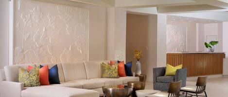 Una sala moderna con un sofá, sillas, una mesa de centro y cojines decorativos.