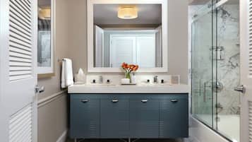 A bathroom with a double vanity, a glass-enclosed shower, and a mirror above the sink.