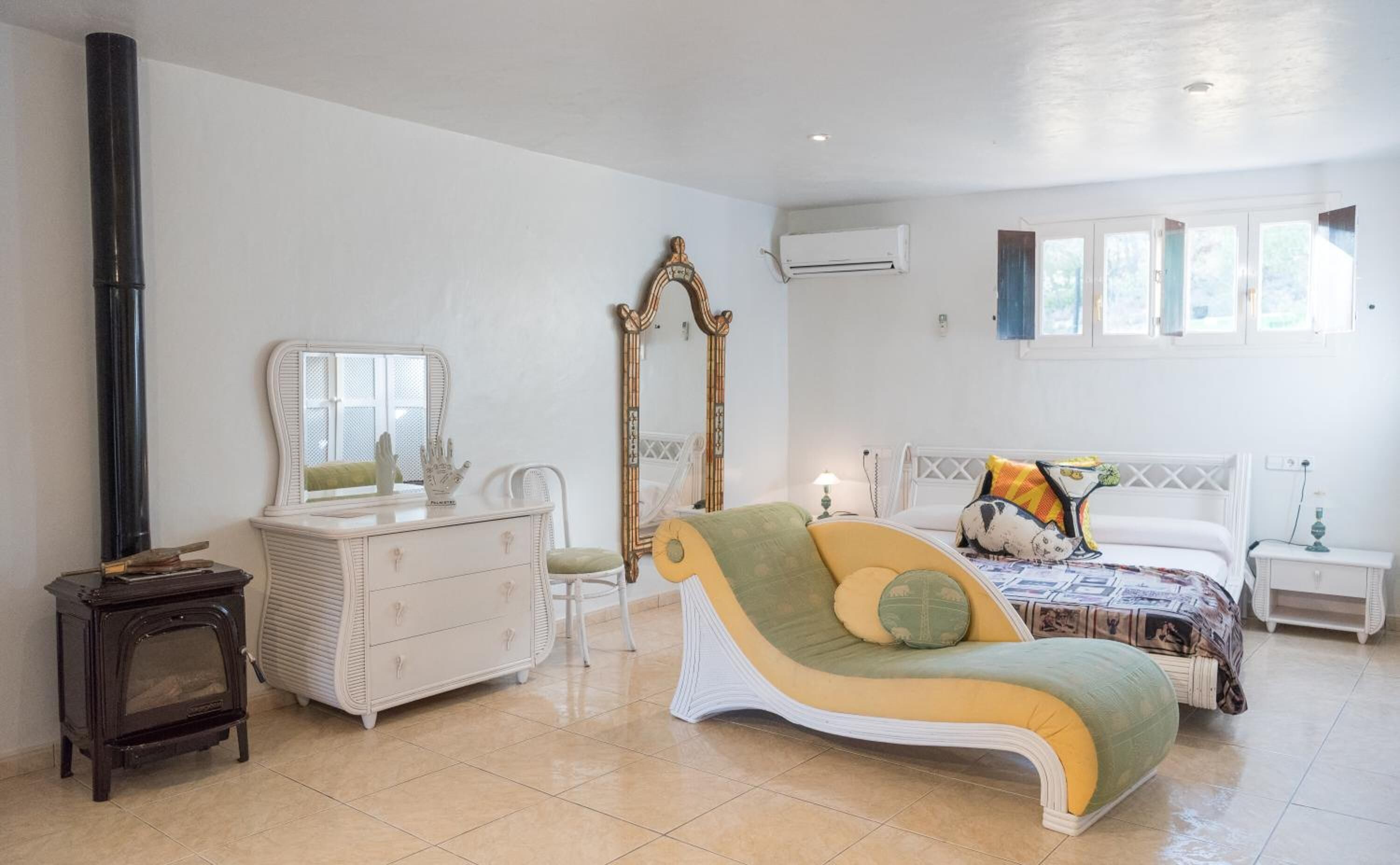 A bedroom with a bed, a dresser, a mirror, a vanity, and a radiator.